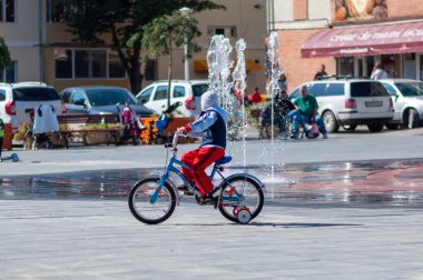 Timisoara, Romanya - 27 Eylül 2014: Çocuk bisikletini çeşmenin yanında sürüyor