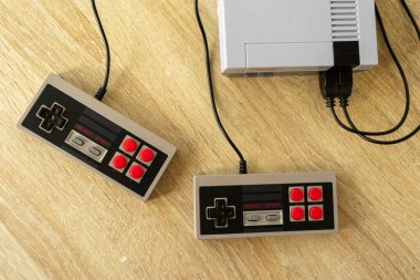 Tahta bir masada klasik oyun konsolu ve oyun konsolu.