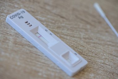 Tahta bir masa üzerinde COVID-19 testi ve bir örnek testi.