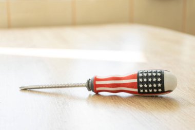 Tahta bir masanın üzerinde Amerikan bayrağı olan tornavida.