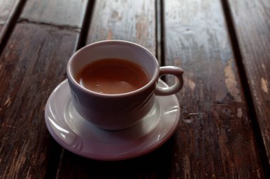 Tahta bir masanın üzerinde kahve olan bir fincanın yakın çekimi.