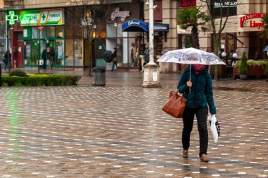 Timisoara, Romanya - 23 Mart 2016: Elinde şemsiyeyle sokakta yürüyen kadın. Gerçek insanlar..