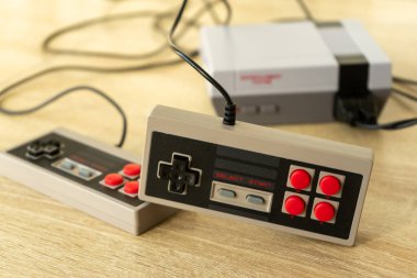 Tahta bir masada klasik oyun konsolu ve oyun konsolu.