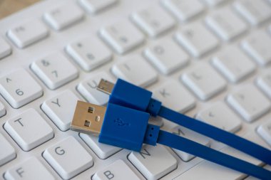 Close-up on a micro USB cable with a white keyboard in the background