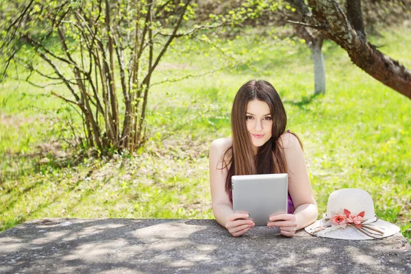 Jonge vrouw met behulp van digitale tablet buitenshuis op zomerdag — Stockfoto