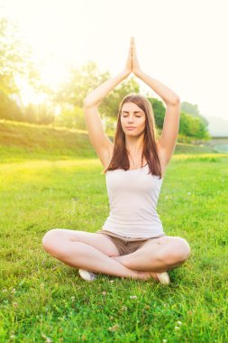 sevimli genç bir kadın açık havada yoga yaparken
