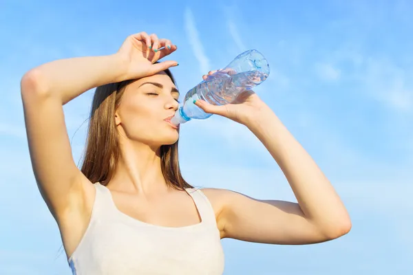 Leuke jonge vrouw drinkwater na training Stockfoto
