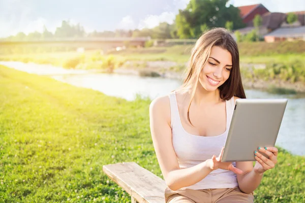 Young student girl sitting on a bench using tablet computer — Stock Photo, Image