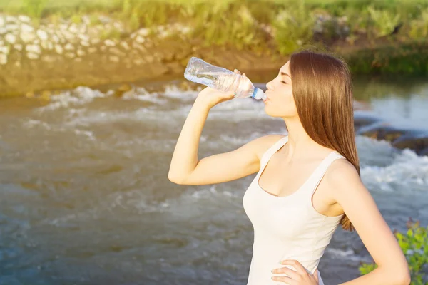 Tired young woman drinking water — Stock Photo, Image