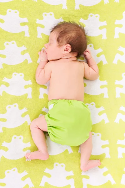 Прекрасный ребенок в зеленых подгузниках спит на животе — стоковое фото