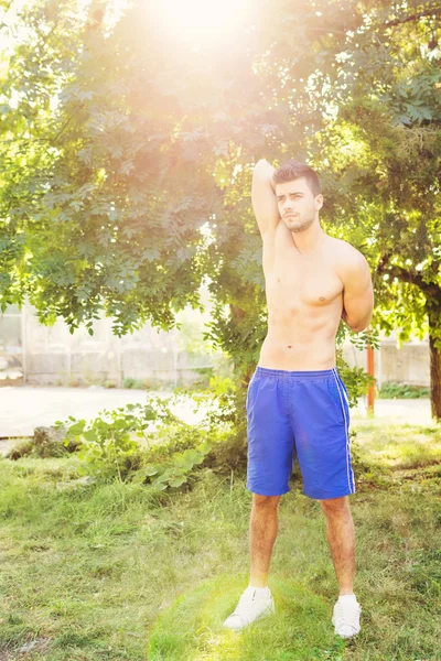 Handsome young guy stretching his triceps after workout — Stock Photo, Image