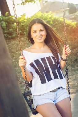 Genç öğrenci kız parkta salıncak üzerinde