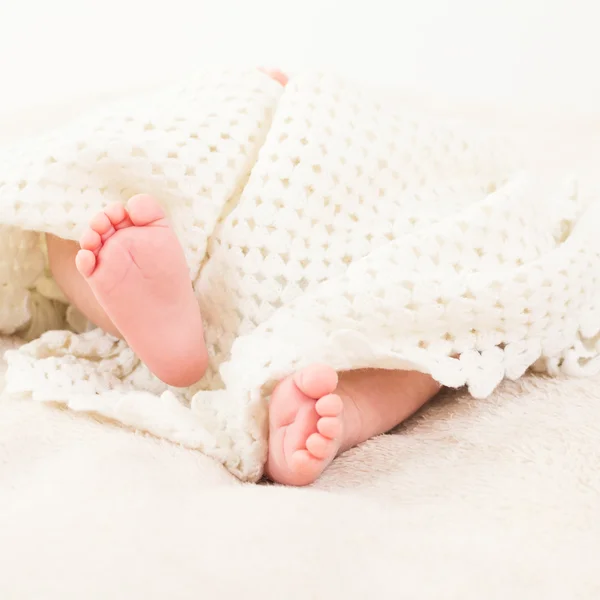 Baby covered with white soft blanket showing feet — Stock Photo, Image