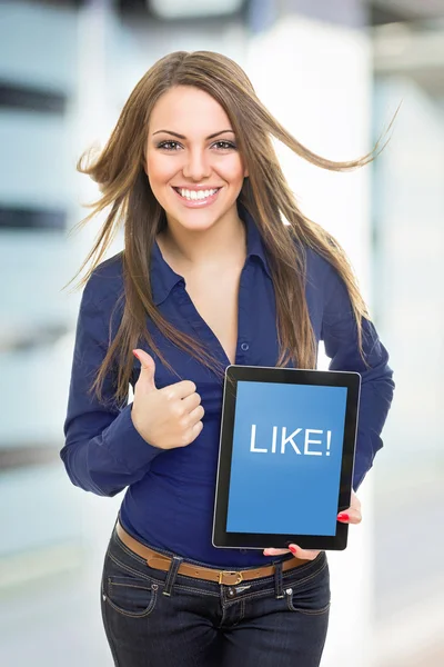 Hermosa mujer joven mostrando la pantalla de la tableta que dice como — Foto de Stock