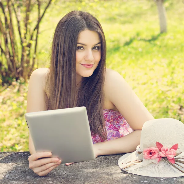 Szczęśliwa młoda kobieta z komputera typu tablet w parku — Zdjęcie stockowe