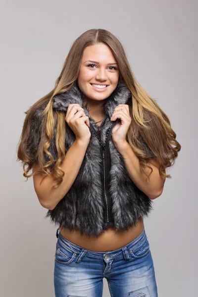Çekici genç kız gülümseyerek kısa kürk palto giyiyor — Stok fotoğraf