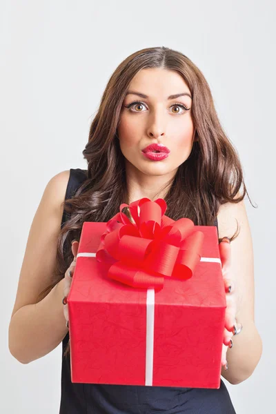 Surprised young woman showing big red gift box — Stock Photo, Image