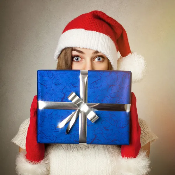Cute teenage girl with Santa hat holding blue gift box — Stock Photo, Image