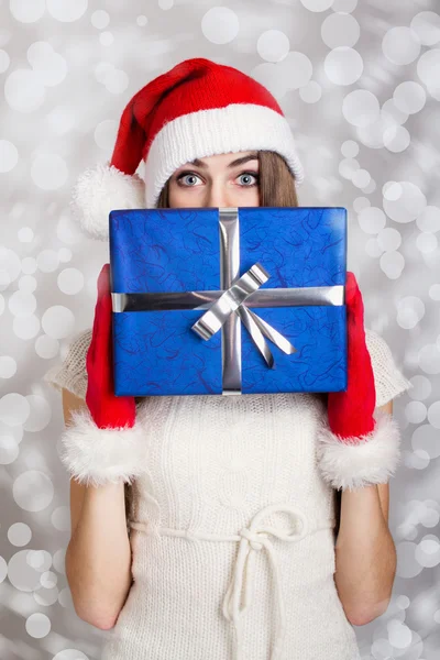 Söta tonårsflicka med santa hatt hålla blå presentask mot snö bakgrunden — Stockfoto