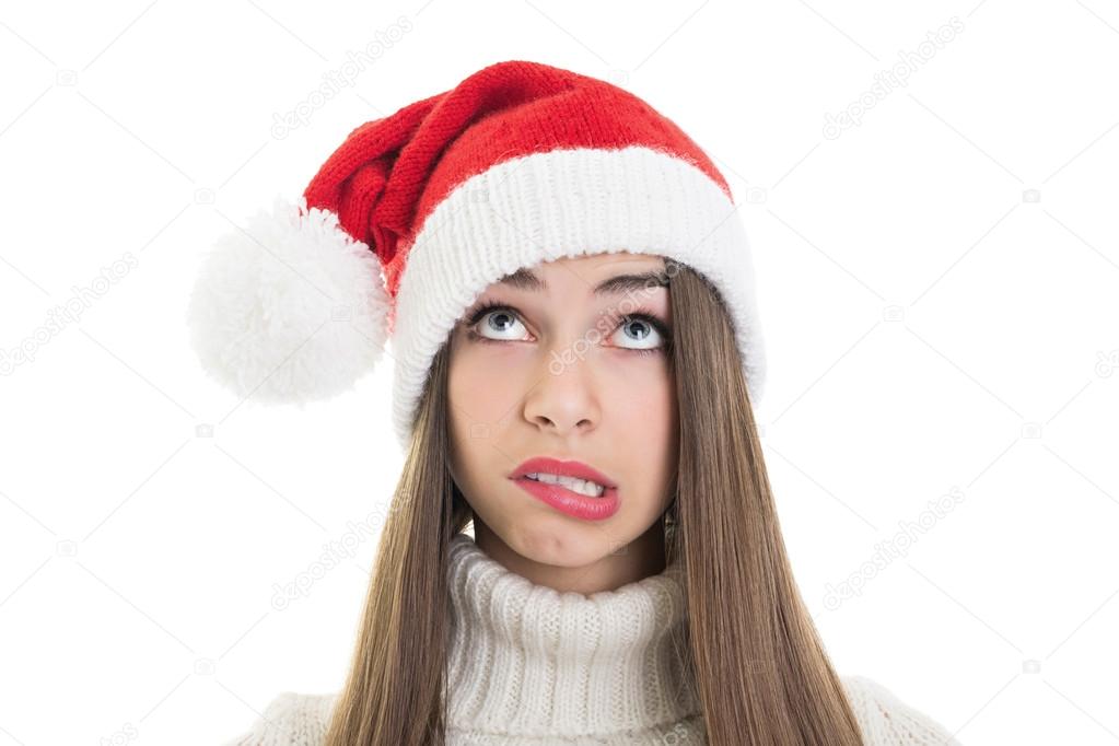 Confused teenage girl wearing Santa beanie hat looking up