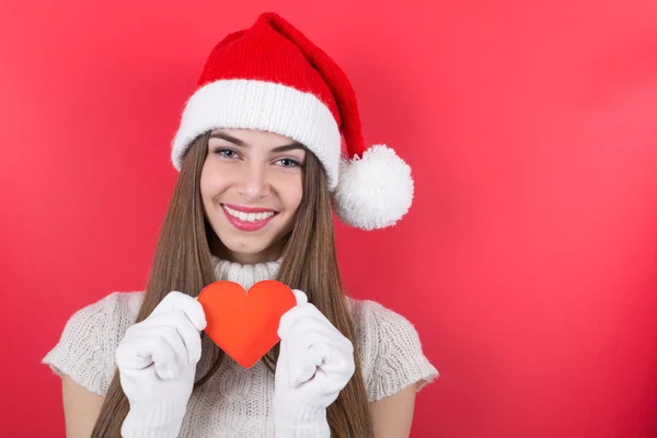 Cute happy teenage girl with Santa hat showing paper heart — Stock Photo, Image
