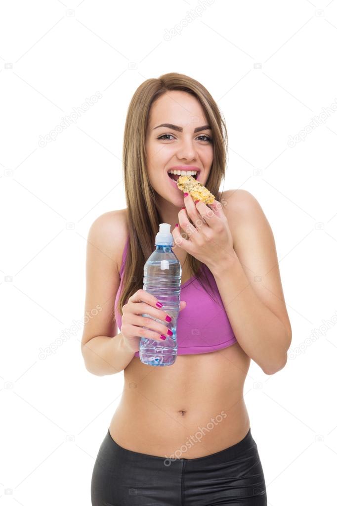 Fitness woman eating cereal bar and drinking water