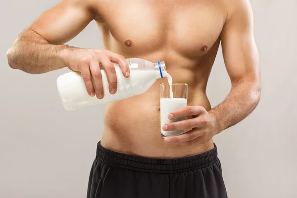 Healthy fit muscular shirtless man pouring milk — Stock Photo, Image