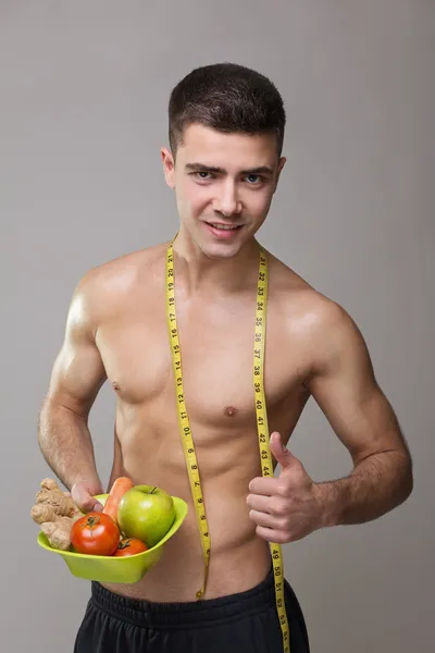 Fit vegan man with measuring tape and healthy food — Stock Photo, Image