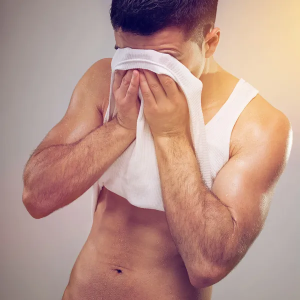 Müder fitter junger Mann wischt sich den Schweiß aus dem Gesicht — Stockfoto