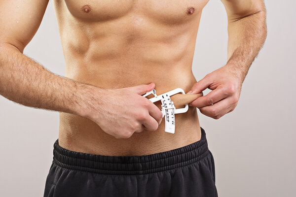 Fit sportsman measuring body fat with caliper