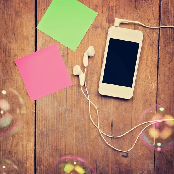 kulaklıklar ve ahşap yüzey üzerinde yapışkan notlar ile Smartphone