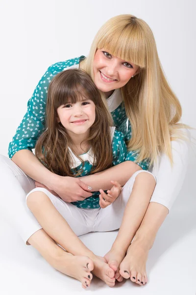 Mãe e filha com cabelos longos com franja abraçando e sorrindo — Fotografia de Stock