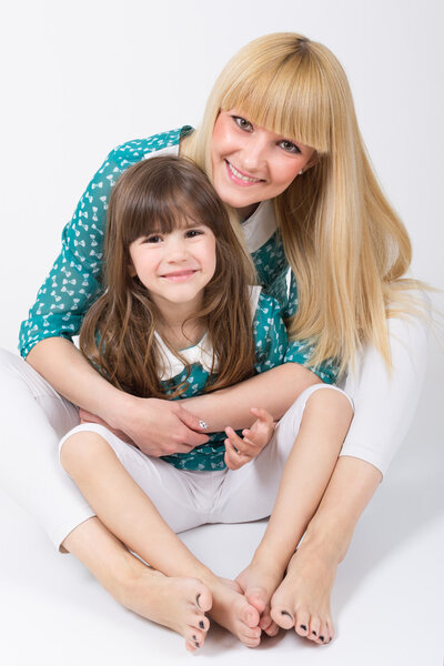 Mother and daughter with long hair with bangs hugging and smiling