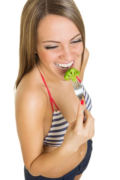 Apto jovem mulher em biquíni comer brócolis — Fotografia de Stock