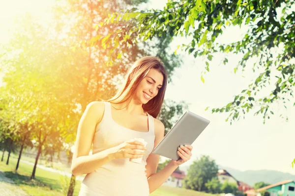 Menina adolescente bonito com tablet e takeaway café no parque Imagens De Bancos De Imagens Sem Royalties