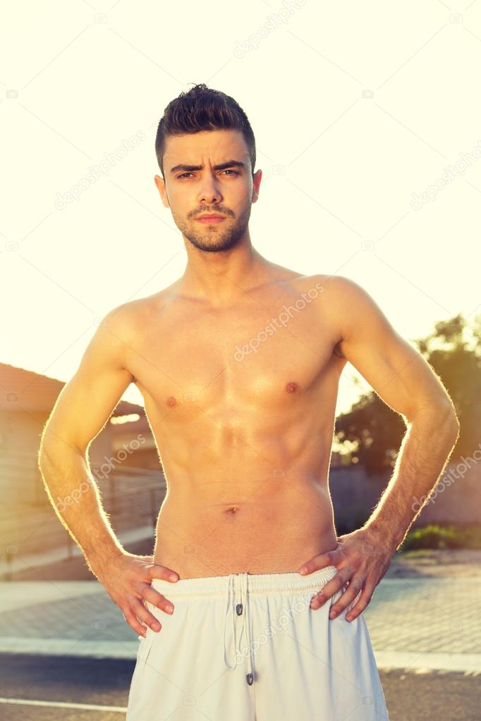 Handsome young shirtless man outdoors in summer