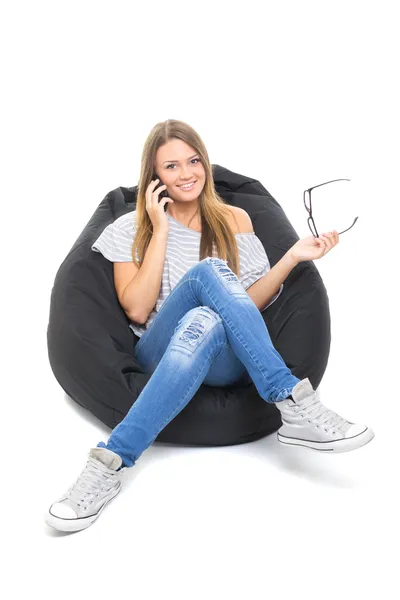 Sevimli genç kız beanbag üzerinde oturan telefonda konuşuyor — Stok fotoğraf