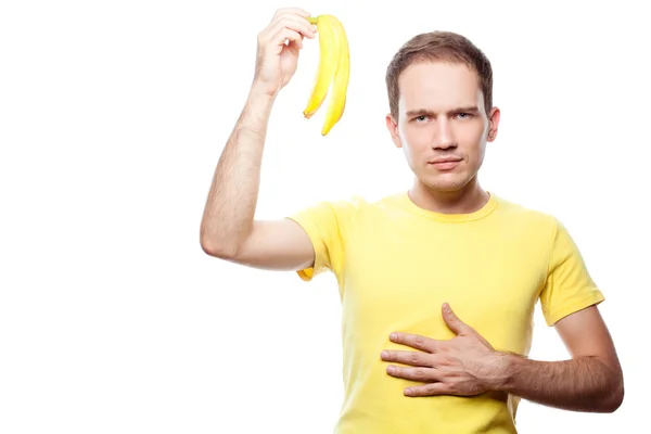 Disappointed and hungry handsome guy holding banana skin over white background — Stock Photo, Image