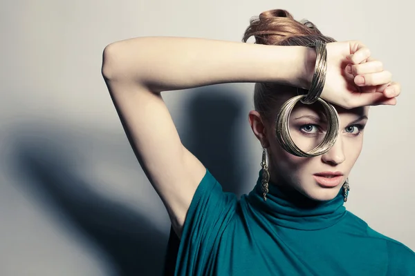 Eine schöne junge Blondine in blauem Kleid trägt Armbänder über g — Stockfoto