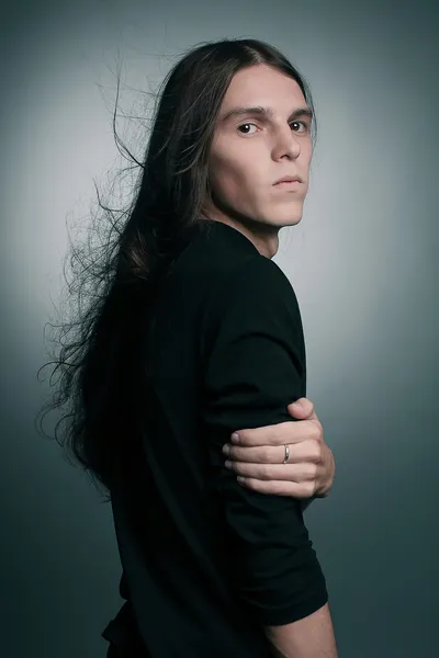 Arty portrait of a fashionable male model with long hair over da — Stock Photo, Image