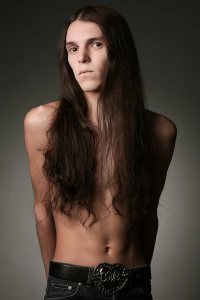 Portrait of a handsome long haired brunet male model over gray b — Stock Photo, Image