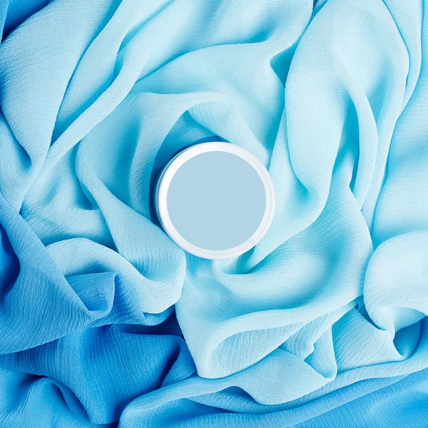 Beauty cream box over turquoise vapory and wavy cloth background — Stock Photo, Image