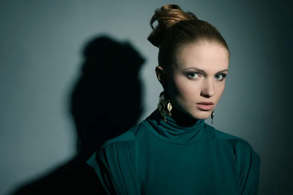 Una hermosa joven rubia vistiendo verde (azul) vestido sobre luz-bl — Foto de Stock