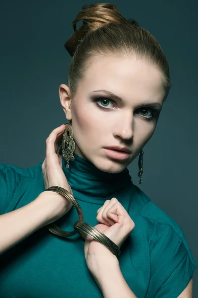 A beautiful young blonde in a green (blue) dress wearing wristba — Stock Photo, Image