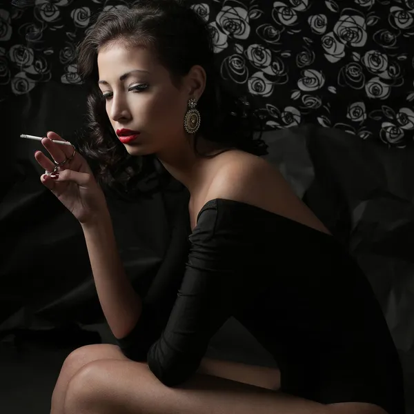 Fumar morena de moda sobre un fondo de papel negro arrugado . — Foto de Stock