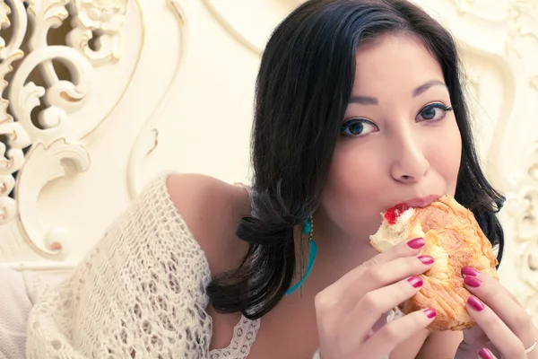 Retrato de uma jovem mulher bonita comendo seu croissant com st — Fotografia de Stock