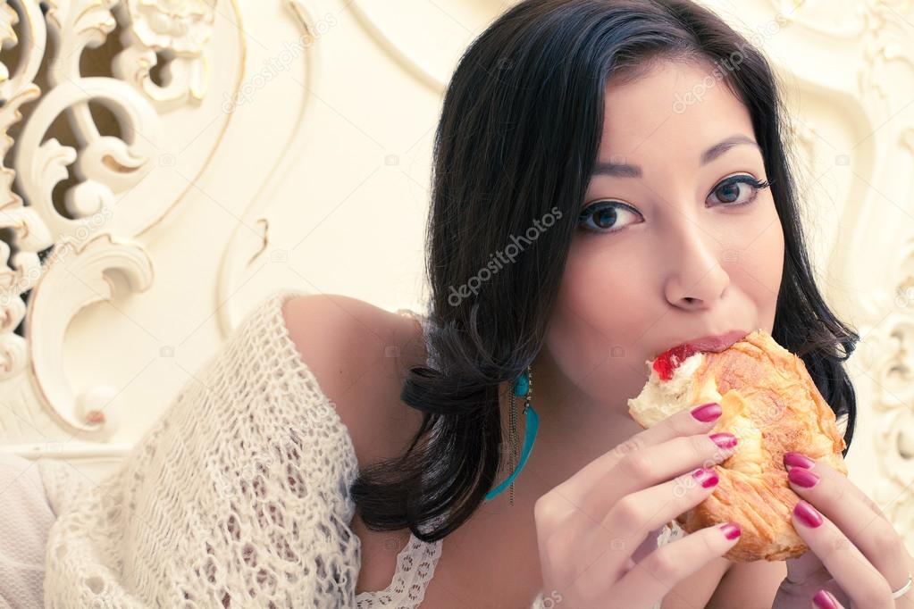 Portrait of a young beautiful woman eating her croissant with st