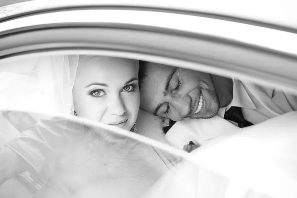 Retrato de um noivo animado abraçar sua noiva no carro e la — Fotografia de Stock