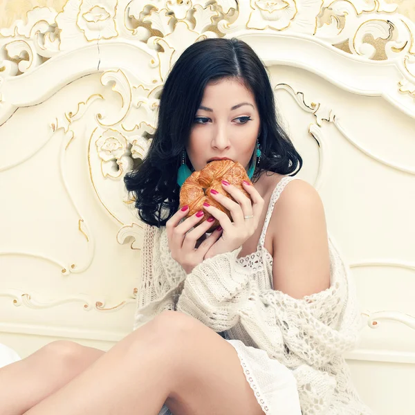 Retrato de una joven hermosa mujer comiendo su croissant y thi — Foto de Stock