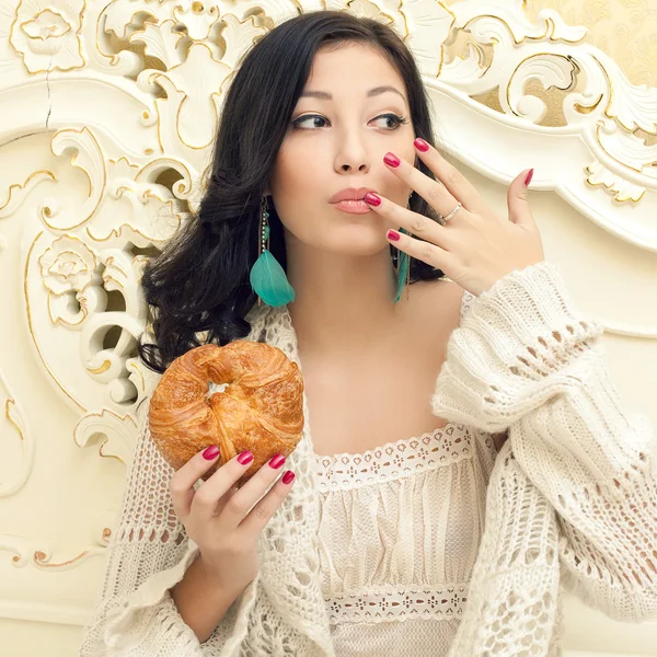 Porträt einer jungen schönen Frau, die ihr Croissant isst und — Stockfoto